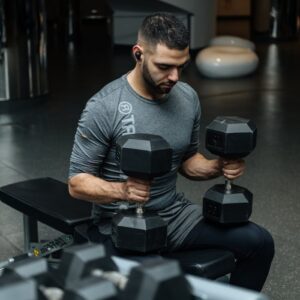 Adult man lifting dumbbells in a gym, focused on strength training workout.